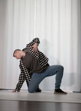 Beyaz arka planda dans eden genç adam. Ekose gömlekle modern dans. Spor plastik hareketler kollar, bacaklar ve gövde.