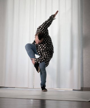 Beyaz arka planda dans eden genç adam. Ekose gömlekle modern dans. Spor plastik hareketler kollar, bacaklar ve gövde.