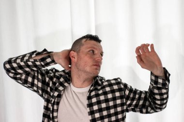 Beyaz arka planda dans eden genç adam. Ekose gömlekle modern dans. Spor plastik hareketler kollar, bacaklar ve gövde.