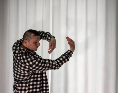 Beyaz arka planda dans eden genç adam. Ekose gömlekle modern dans. Spor plastik hareketler kollar, bacaklar ve gövde.