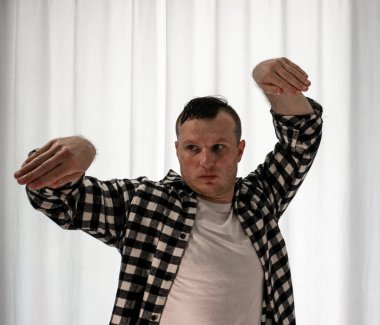 Beyaz arka planda dans eden genç adam. Ekose gömlekle modern dans. Spor plastik hareketler kollar, bacaklar ve gövde.