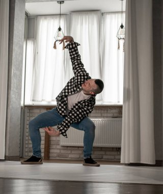 Beyaz arka planda dans eden genç adam. Ekose gömlekle modern dans. Spor plastik hareketler kollar, bacaklar ve gövde.