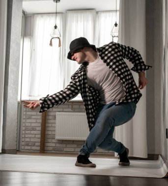 Beyaz arka planda dans eden genç adam. Ekose gömlekle modern dans. Spor plastik hareketler kollar, bacaklar ve gövde.