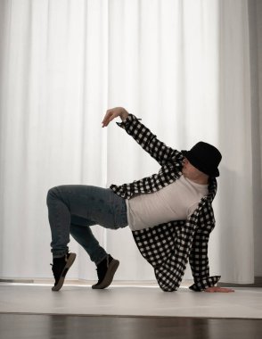 Beyaz arka planda dans eden genç adam. Ekose gömlekle modern dans. Spor plastik hareketler kollar, bacaklar ve gövde.