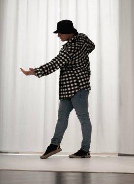 Beyaz arka planda dans eden genç adam. Ekose gömlekle modern dans. Spor plastik hareketler kollar, bacaklar ve gövde.