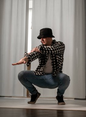 Beyaz arka planda dans eden genç adam. Ekose gömlekle modern dans. Spor plastik hareketler kollar, bacaklar ve gövde.