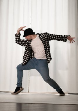 Beyaz arka planda dans eden genç adam. Ekose gömlekle modern dans. Spor plastik hareketler kollar, bacaklar ve gövde.