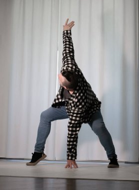 Beyaz arka planda dans eden genç adam. Ekose gömlekle modern dans. Spor plastik hareketler kollar, bacaklar ve gövde.