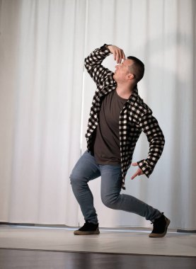 Beyaz arka planda dans eden genç adam. Ekose gömlekle modern dans. Spor plastik hareketler kollar, bacaklar ve gövde.