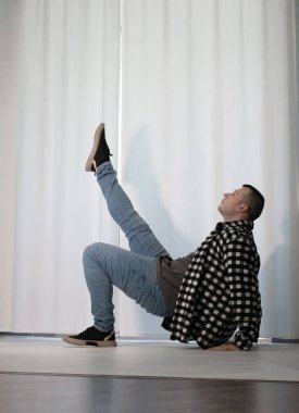 Beyaz arka planda dans eden genç adam. Ekose gömlekle modern dans. Spor plastik hareketler kollar, bacaklar ve gövde.