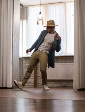 Genç dansçı poz veriyor. Gündelik kıyafetlerle modern bir dans sergileyen bir adam..