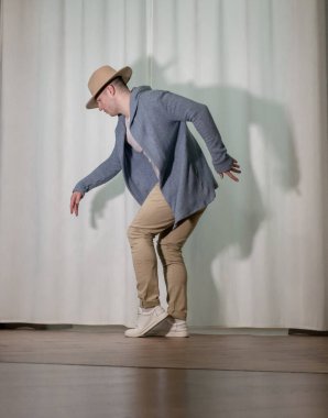 Genç dansçı poz veriyor. Gündelik kıyafetlerle modern bir dans sergileyen bir adam..