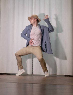 Genç dansçı poz veriyor. Gündelik kıyafetlerle modern bir dans sergileyen bir adam..