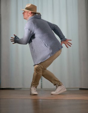Genç dansçı poz veriyor. Gündelik kıyafetlerle modern bir dans sergileyen bir adam..