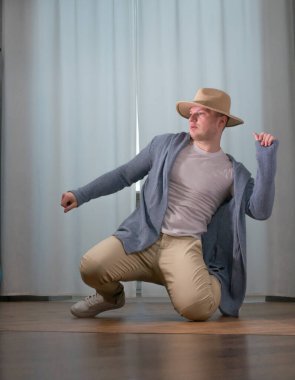 Genç dansçı poz veriyor. Gündelik kıyafetlerle modern bir dans sergileyen bir adam..