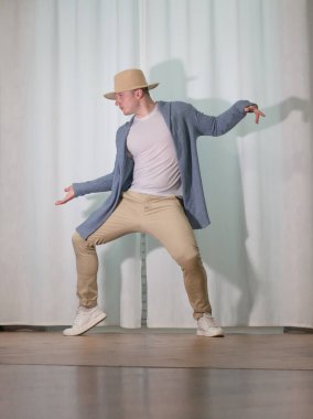 Genç dansçı poz veriyor. Gündelik kıyafetlerle modern bir dans sergileyen bir adam..