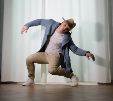 Genç dansçı poz veriyor. Gündelik kıyafetlerle modern bir dans sergileyen bir adam..