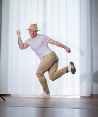 Genç dansçı poz veriyor. Gündelik kıyafetlerle modern bir dans sergileyen bir adam..