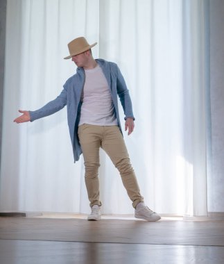 Genç dansçı poz veriyor. Gündelik kıyafetlerle modern bir dans sergileyen bir adam..