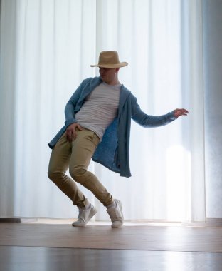 Genç dansçı poz veriyor. Gündelik kıyafetlerle modern bir dans sergileyen bir adam..