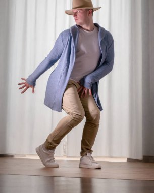 Genç dansçı poz veriyor. Gündelik kıyafetlerle modern bir dans sergileyen bir adam..
