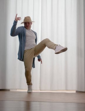 Genç dansçı poz veriyor. Gündelik kıyafetlerle modern bir dans sergileyen bir adam..