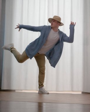Genç dansçı poz veriyor. Gündelik kıyafetlerle modern bir dans sergileyen bir adam..