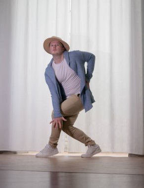 Genç dansçı poz veriyor. Gündelik kıyafetlerle modern bir dans sergileyen bir adam..