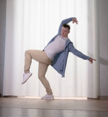 Genç dansçı poz veriyor. Gündelik kıyafetlerle modern bir dans sergileyen bir adam..