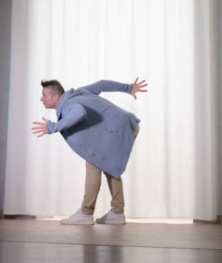Genç dansçı poz veriyor. Gündelik kıyafetlerle modern bir dans sergileyen bir adam..