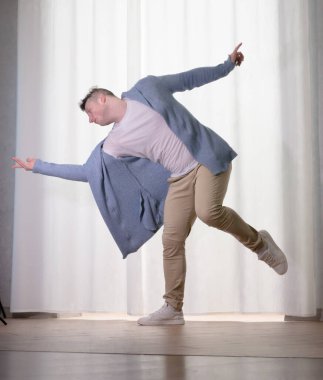 Genç dansçı poz veriyor. Gündelik kıyafetlerle modern bir dans sergileyen bir adam..