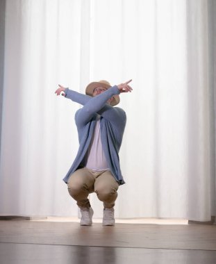 Genç dansçı poz veriyor. Gündelik kıyafetlerle modern bir dans sergileyen bir adam..