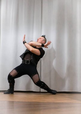 Rock kostümlü bir adam dans figürleri sergiler. Kafasında mohawk olan metal bir adam. Hareket eden adam ve dans eden kollar ve bacaklar..