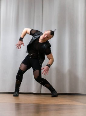 Rock kostümlü bir adam dans figürleri sergiler. Kafasında mohawk olan metal bir adam. Hareket eden adam ve dans eden kollar ve bacaklar..