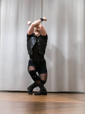 Rock kostümlü bir adam dans figürleri sergiler. Kafasında mohawk olan metal bir adam. Hareket eden adam ve dans eden kollar ve bacaklar..