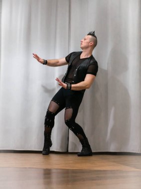 Rock kostümlü bir adam dans figürleri sergiler. Kafasında mohawk olan metal bir adam. Hareket eden adam ve dans eden kollar ve bacaklar..