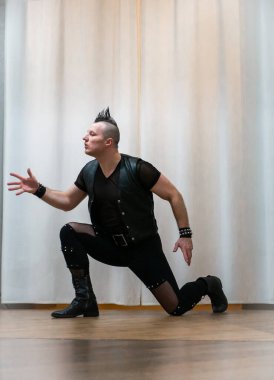 Rock kostümlü bir adam dans figürleri sergiler. Kafasında mohawk olan metal bir adam. Hareket eden adam ve dans eden kollar ve bacaklar..