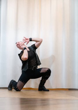 Rock kostümlü bir adam dans figürleri sergiler. Kafasında mohawk olan metal bir adam. Hareket eden adam ve dans eden kollar ve bacaklar..