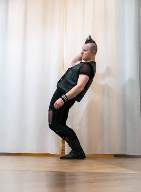 Rock kostümlü bir adam dans figürleri sergiler. Kafasında mohawk olan metal bir adam. Hareket eden adam ve dans eden kollar ve bacaklar..