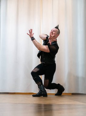 Rock kostümlü bir adam dans figürleri sergiler. Kafasında mohawk olan metal bir adam. Hareket eden adam ve dans eden kollar ve bacaklar..