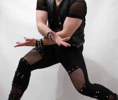 Rock kostümlü bir adam dans figürleri sergiler. Kafasında mohawk olan metal bir adam. Hareket eden adam ve dans eden kollar ve bacaklar..