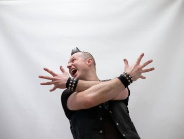 Rock kostümlü bir adam dans figürleri sergiler. Kafasında mohawk olan metal bir adam. Hareket eden adam ve dans eden kollar ve bacaklar..