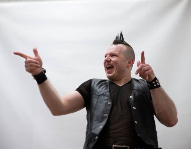 Rock kostümlü bir adam dans figürleri sergiler. Kafasında mohawk olan metal bir adam. Hareket eden adam ve dans eden kollar ve bacaklar..