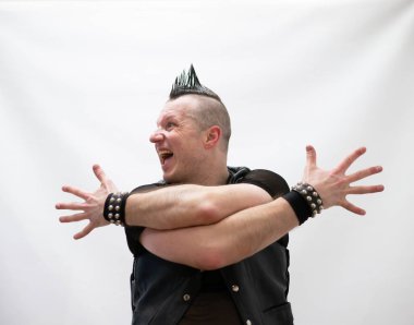 Rock kostümlü bir adam dans figürleri sergiler. Kafasında mohawk olan metal bir adam. Hareket eden adam ve dans eden kollar ve bacaklar..