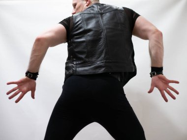 Rock kostümlü bir adam dans figürleri sergiler. Kafasında mohawk olan metal bir adam. Hareket eden adam ve dans eden kollar ve bacaklar..