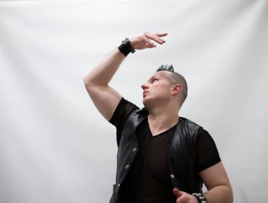 Rock kostümlü bir adam dans figürleri sergiler. Kafasında mohawk olan metal bir adam. Hareket eden adam ve dans eden kollar ve bacaklar..