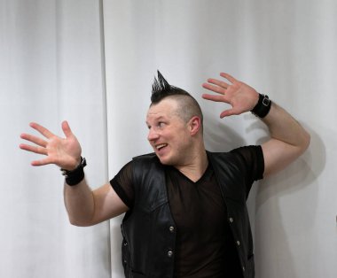 Rock kostümlü bir adam dans figürleri sergiler. Kafasında mohawk olan metal bir adam. Hareket eden adam ve dans eden kollar ve bacaklar..