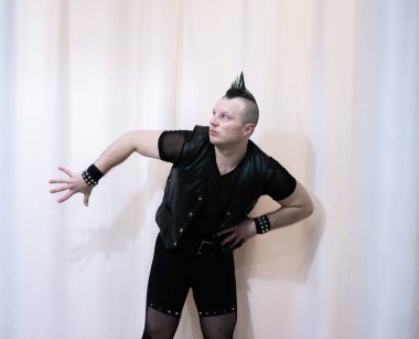 Rock kostümlü bir adam dans figürleri sergiler. Kafasında mohawk olan metal bir adam. Hareket eden adam ve dans eden kollar ve bacaklar..