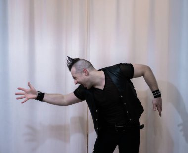 Rock kostümlü bir adam dans figürleri sergiler. Kafasında mohawk olan metal bir adam. Hareket eden adam ve dans eden kollar ve bacaklar..