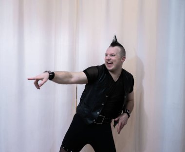 Rock kostümlü bir adam dans figürleri sergiler. Kafasında mohawk olan metal bir adam. Hareket eden adam ve dans eden kollar ve bacaklar..